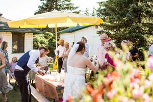 Outdoor wedding reception under yellow tent canopies with guests mingling among colorful flower arrangements.