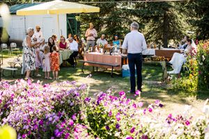 Outdoor wedding reception setup with colorful flowers and a white tent in a garden setting.