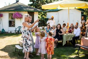 Outdoor wedding reception with yellow tent canopy and guests mingling on the lawn.