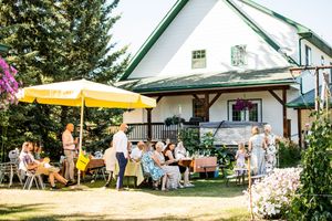 White houses with green trim line a sunny outdoor venue space with yellow umbrellas.