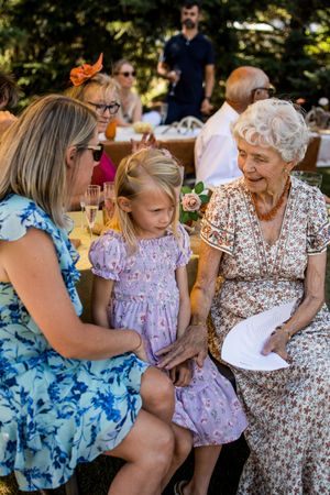 Multi-generational family gathering outdoors with people in colorful summer attire.