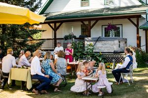 Panoramic view of outdoor wedding reception with white farmhouse and yellow canopy.