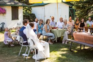 Wedding guests seated in white chairs on a lawn during an outdoor summer reception.