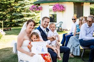 Outdoor wedding reception with tables and chairs set up under trees with hanging floral decorations.