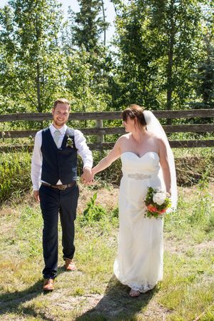A couple shares a playful moment during their wedding photoshoot in a sunny outdoor setting.