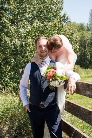 Newlyweds sharing a romantic moment against a rustic wooden fence.