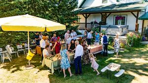 A panoramic view of an outdoor wedding reception with yellow umbrellas and guests seated at tables.