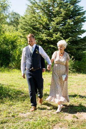 A couple walks together through a sunny garden setting during their wedding celebration.