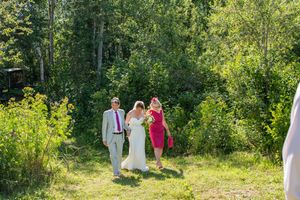 A group of people walking through a lush green forest trail on a sunny summer day.