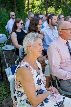 Wedding ceremony guests seated outdoors enjoy the proceedings on a sunny day.