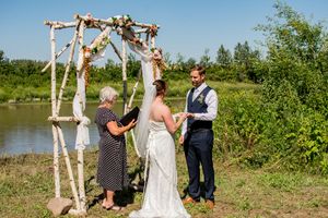 A wedding ceremony setup with birch tree arch and guests gathering outdoors.