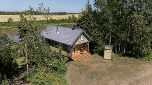 Aerial panorama of rural property with trees and buildings on sunny day.