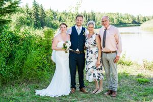 Wedding party posing for photos by a lake on a sunny summer day.