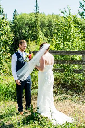 Wedding couple shares a first look moment in a lush green outdoor setting.