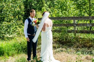 Newlyweds share a moment together by a rustic wooden fence in a garden setting.