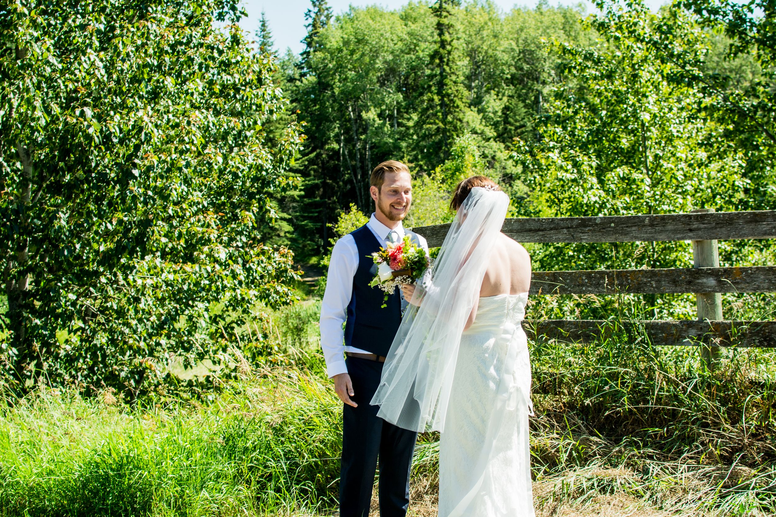 Outdoor wedding ceremony setup with white chairs and floral arrangements in a lush garden setting.