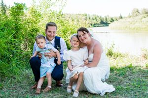 Family members gather for formal wedding photos by a lakeside setting.