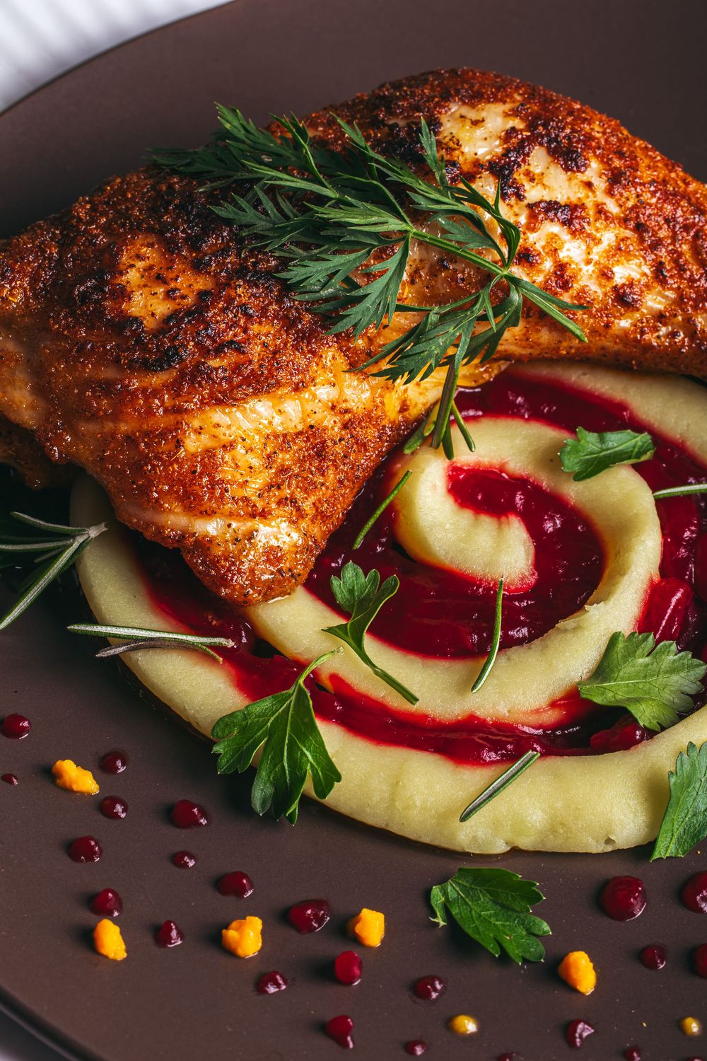 Crusted chicken breast with herb garnish served over potato puree and red wine reduction sauce.