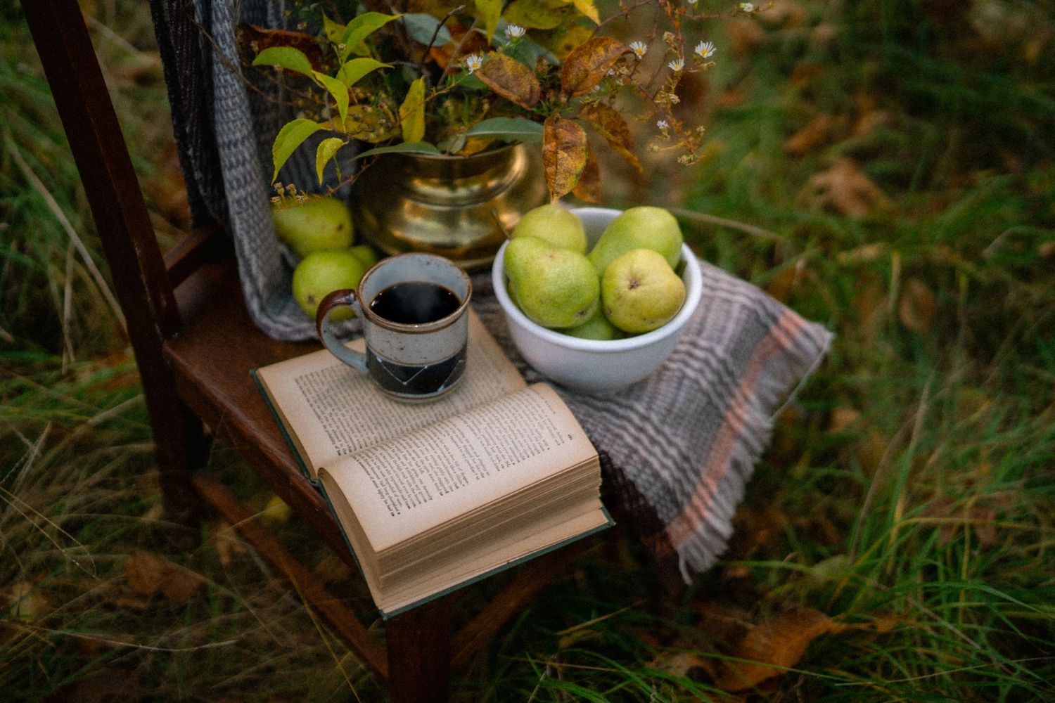 Fresh apples and a glass bottle arranged on rustic wooden crates in an autumn garden setting.