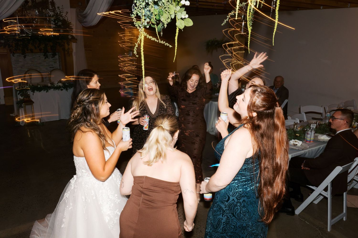 Wedding guests dancing and enjoying themselves on a dimly lit dance floor at an indoor reception celebration.