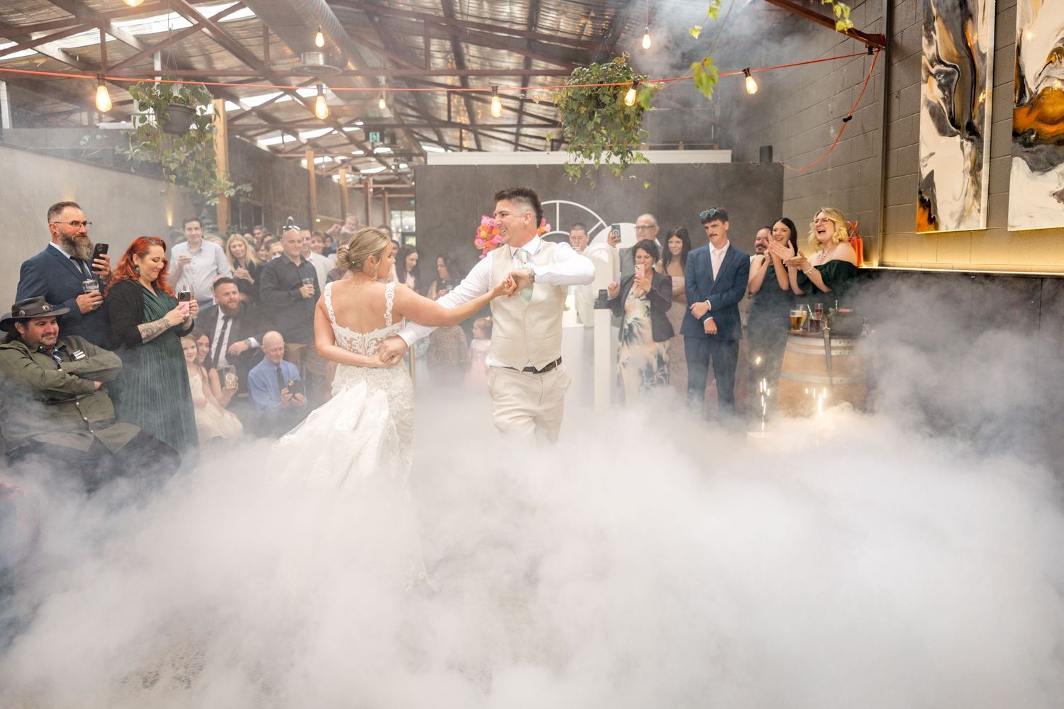 Wedding couple shares joyful laughter while holding floral bouquets in outdoor garden setting.