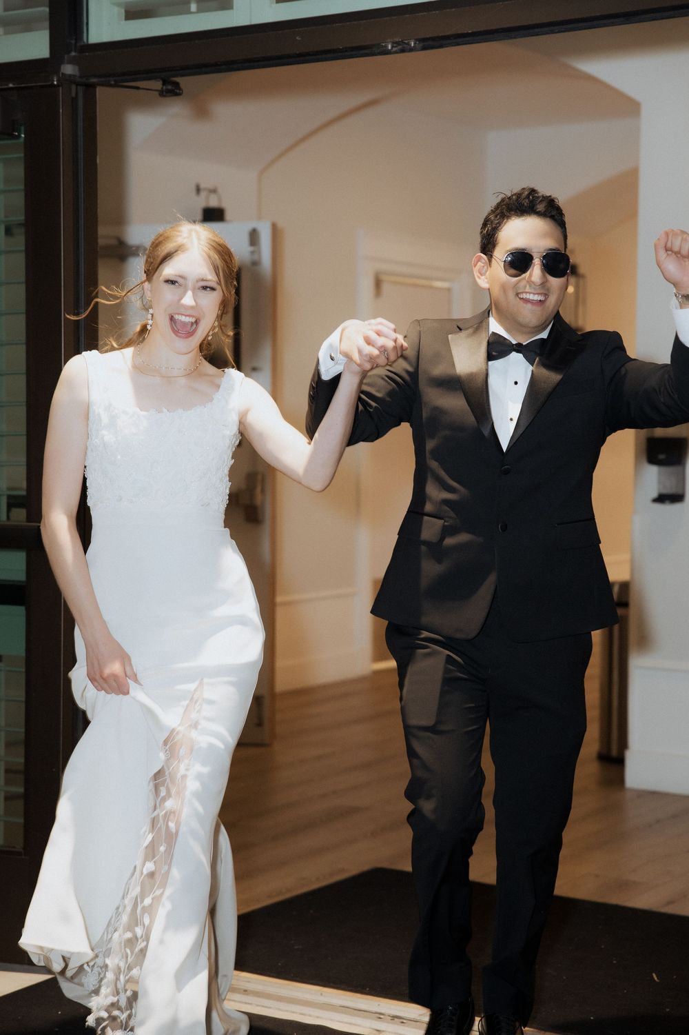 A couple in wedding attire dancing together at a reception, with the bride in white and groom in black suit.