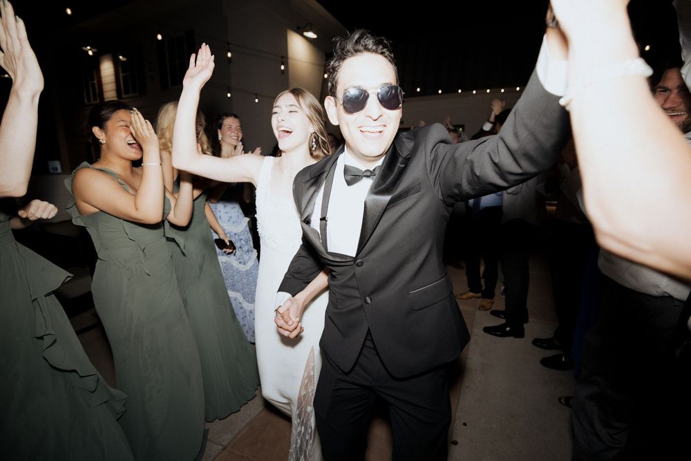 Crowd of people dancing and socializing at a dimly lit nightclub or party venue.