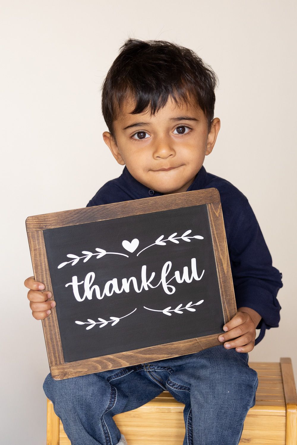 A child looks serious while holding a thankful sign during his preschool picture day in the Bay Area