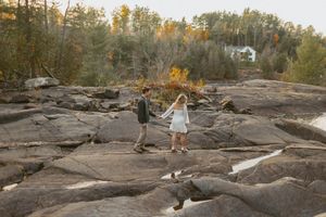 A couple walking hand in hand across rocky terrain during golden hour.