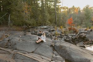 A person in white dress sitting on dramatic rocky landscape during sunset.