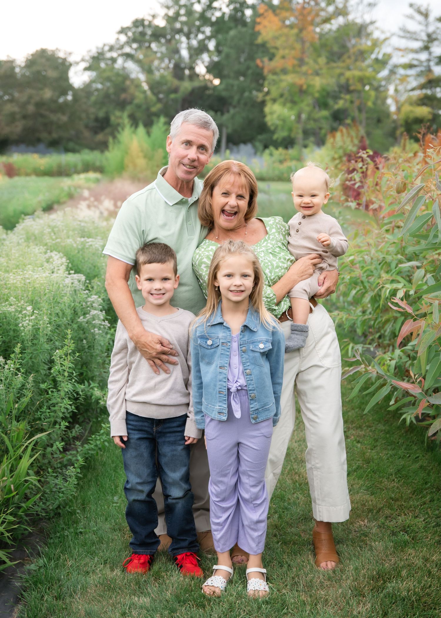 Family enjoying a fun moment together in a lush green garden path during autumn.