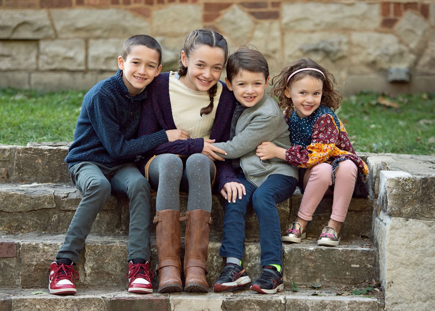 Four siblings sitting together on stone front steps