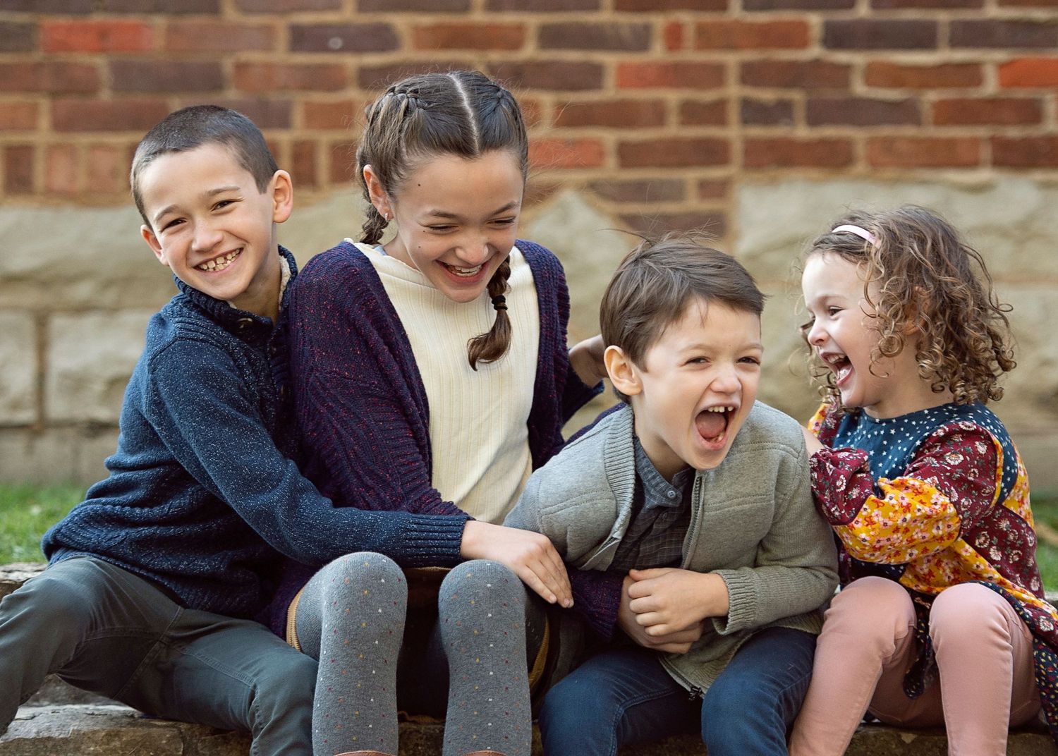 Four siblings sitting together on stone front steps