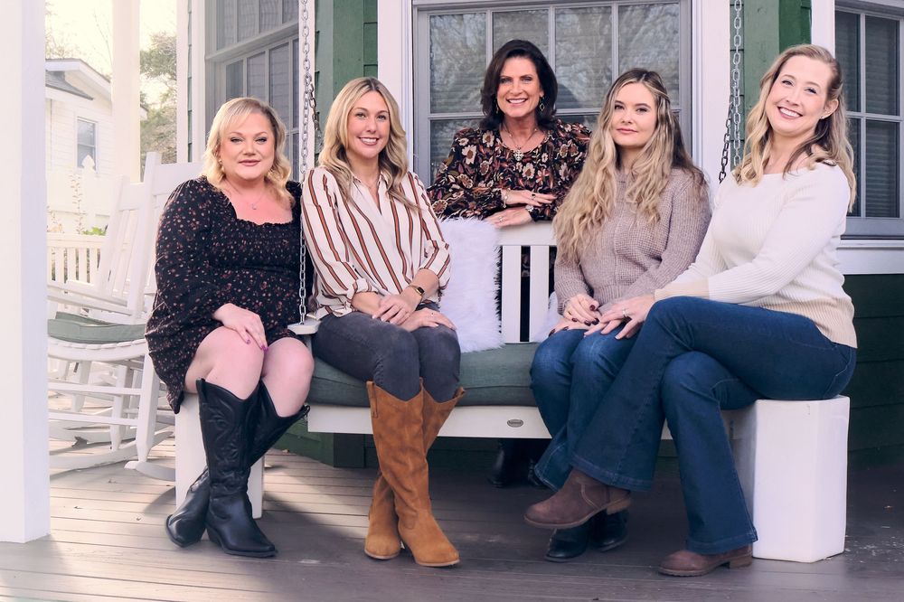 A group of people sit together on white steps, wearing casual fall clothing and boots.