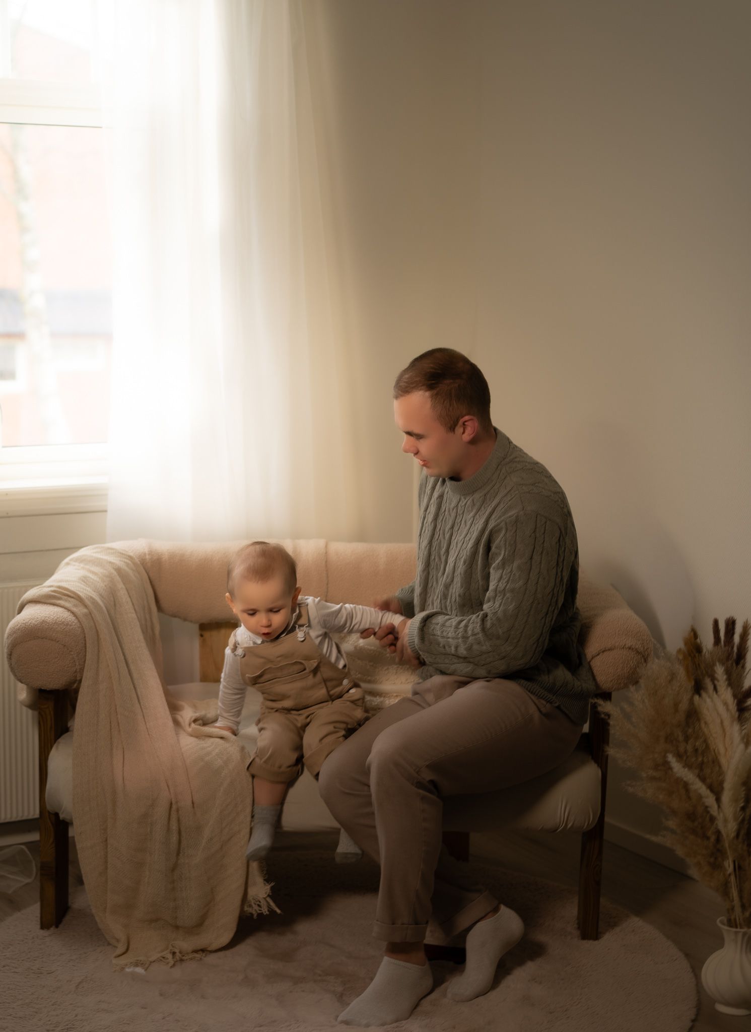 Cozy living room scene with soft natural light streaming through windows and pampas grass decor.