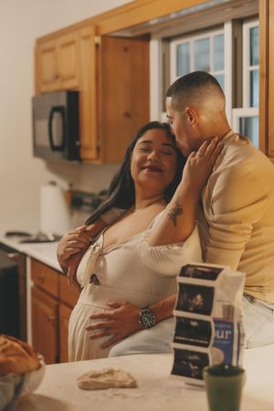 Couple shares tender moments in their kitchen while looking at ultrasound photos together.