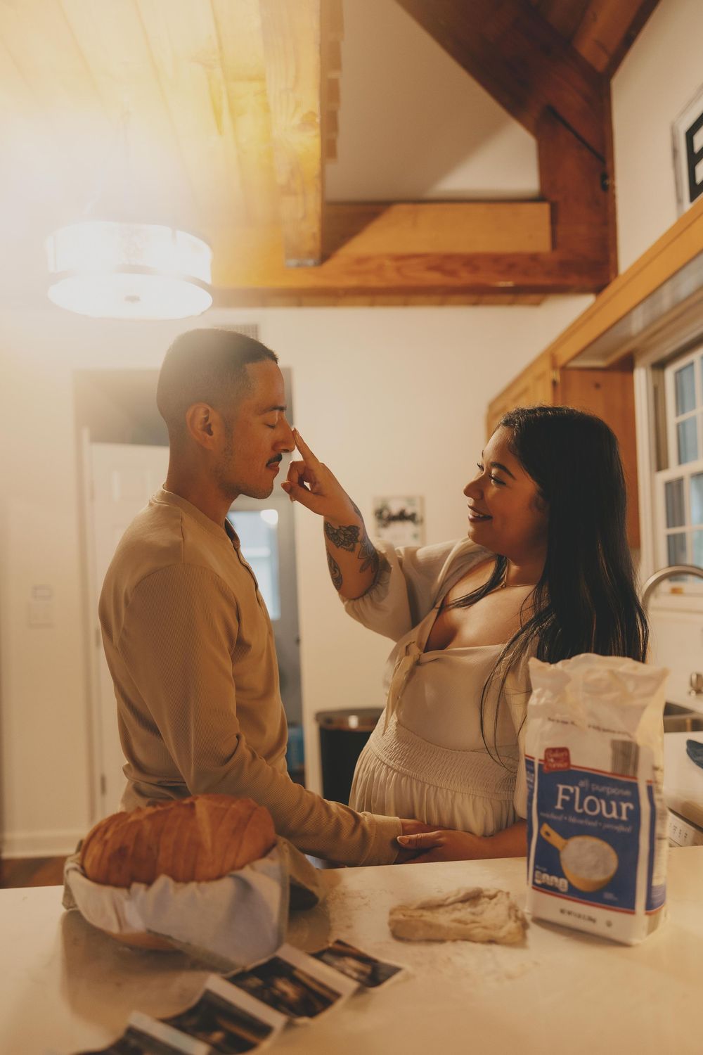 A couple playfully shares intimate moments while baking together in a warmly lit kitchen.