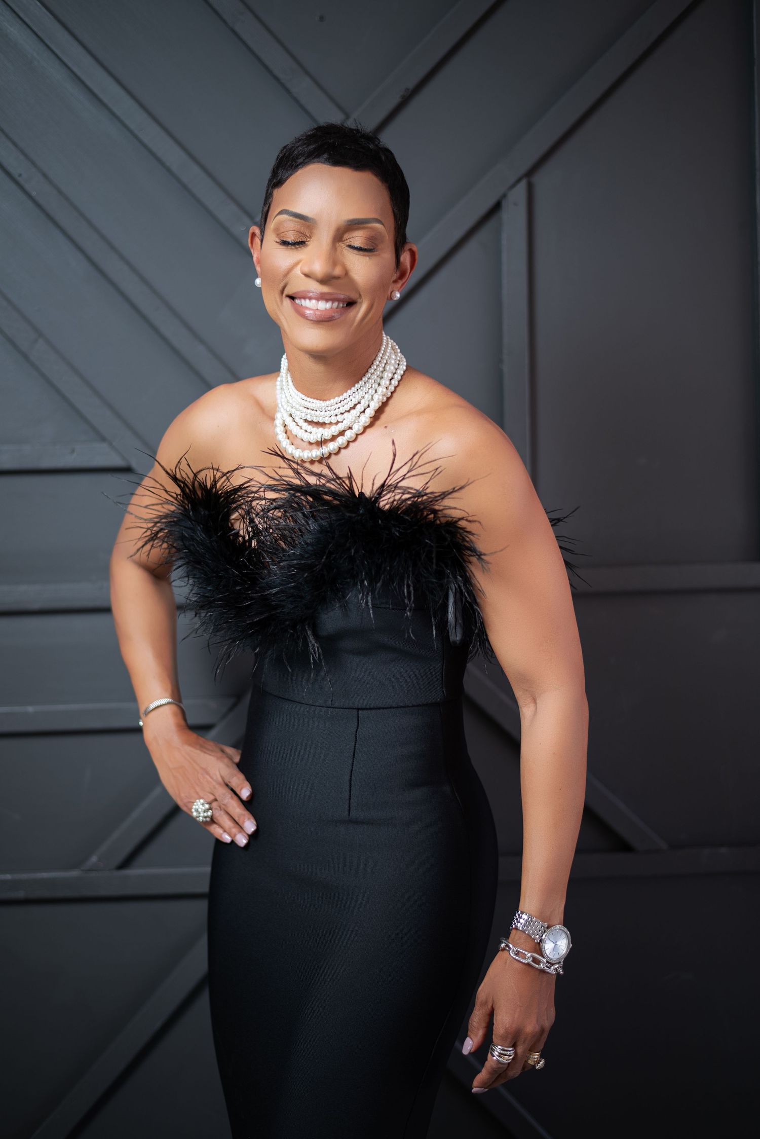 A person in a black strapless dress and pearl necklace poses confidently in a series of elegant portraits.