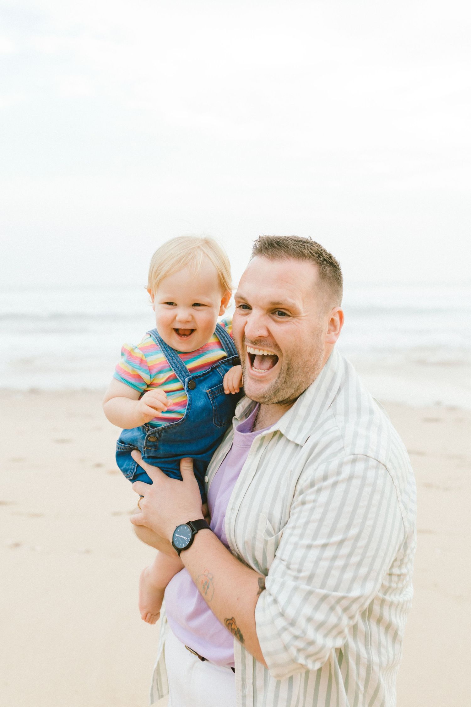 A joyful moment shared between parent and child laughing together on a sunny beach.