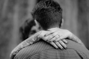 Black and white photo showing couple embracing in an intimate moment with hands around each other.