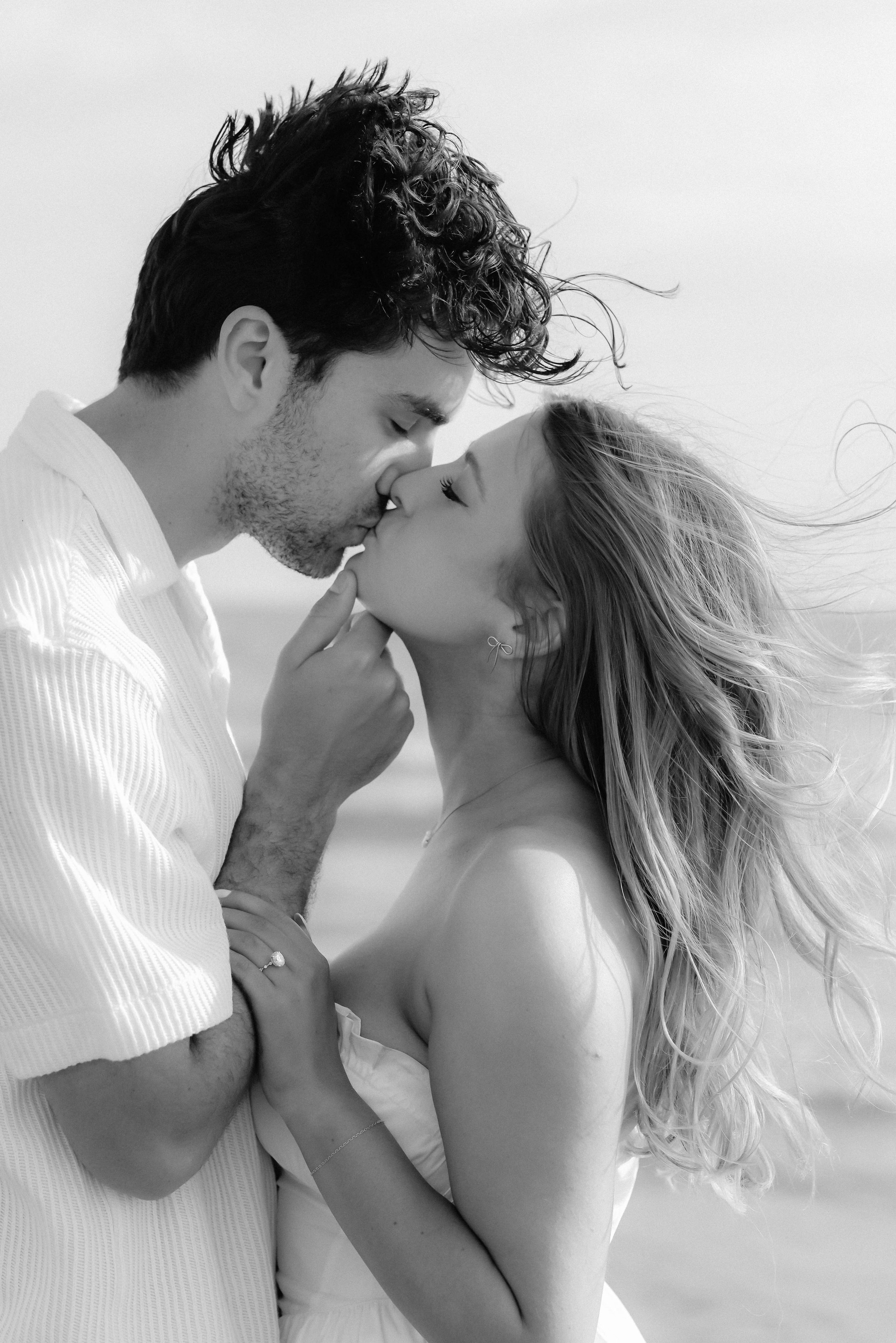 A romantic black and white photo sequence shows a couple sharing an intimate kiss with windswept hair.