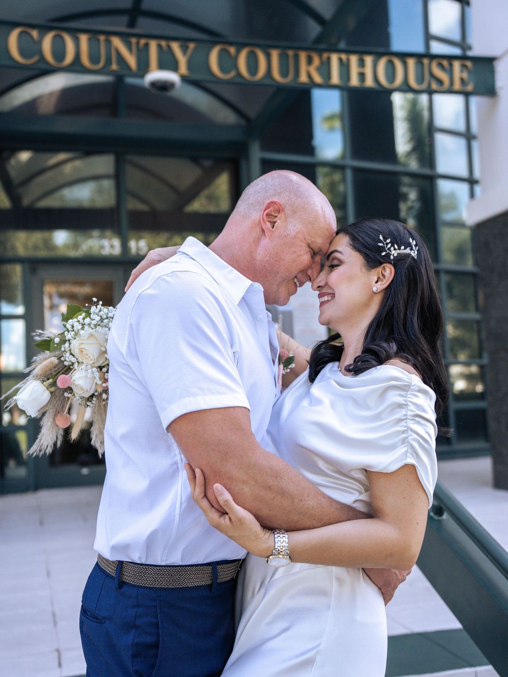 A romantic couple shares joyful moments outside a county courthouse on their wedding day in Naples, Florida