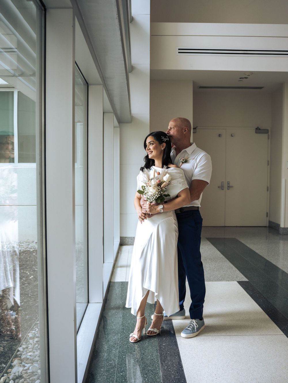 A couple embraces in a sunlit hallway during an intimate courthouse wedding celebration in Naples, Florida
