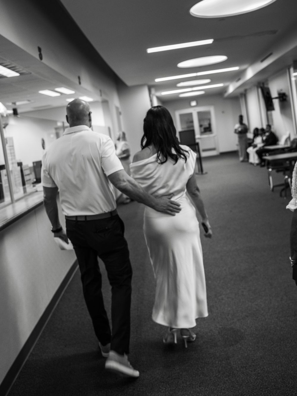 A series of black and white photos showing someone assisting a patient walking down a hospital hallway in Naples, Florida