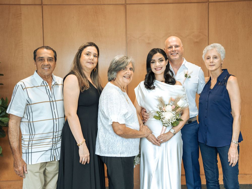 A small group poses together at a wedding celebration, with the bride in white holding a bouquet of flowers in Naples, Florida
