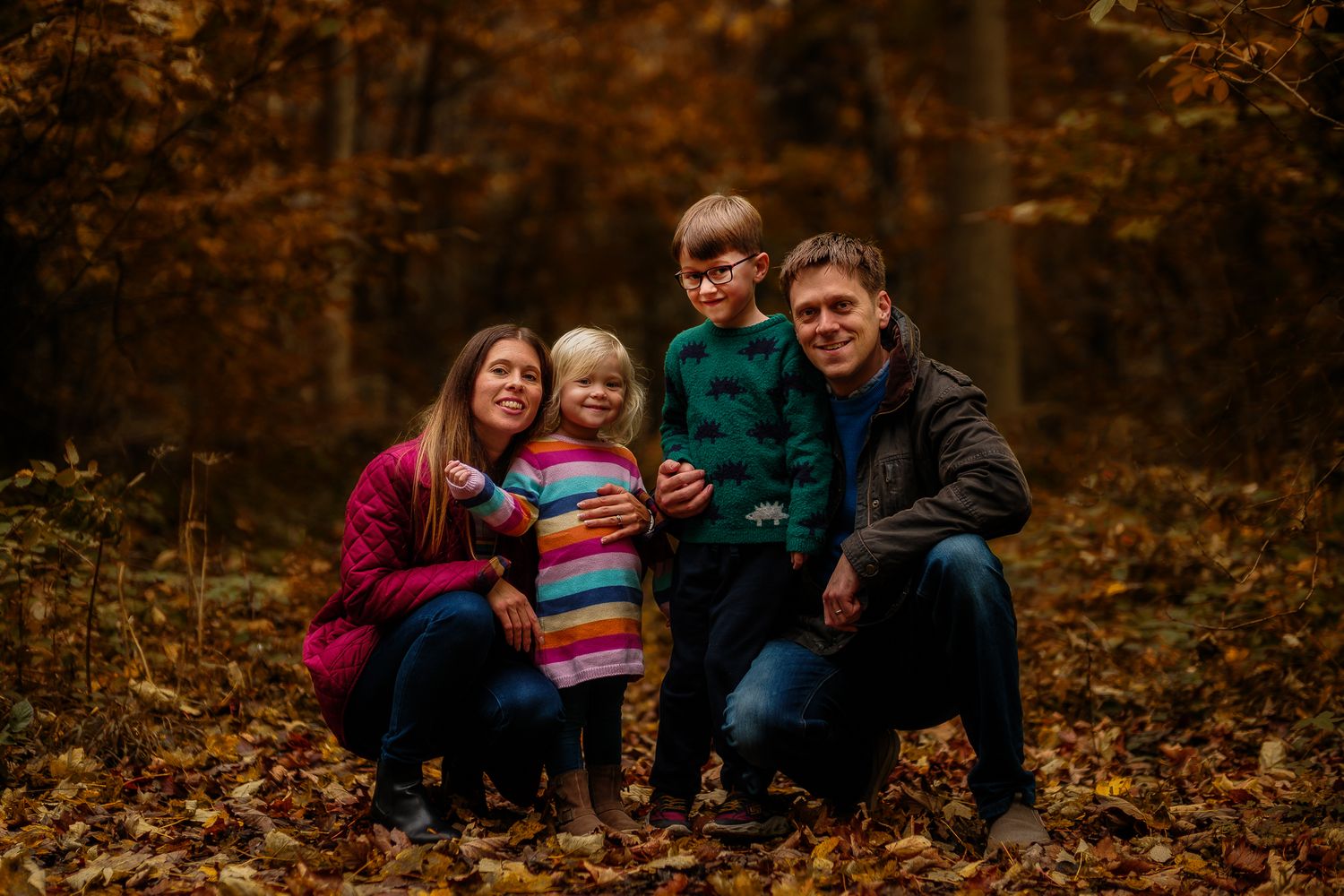 Family of five poses together in a beautiful autumn forest setting.