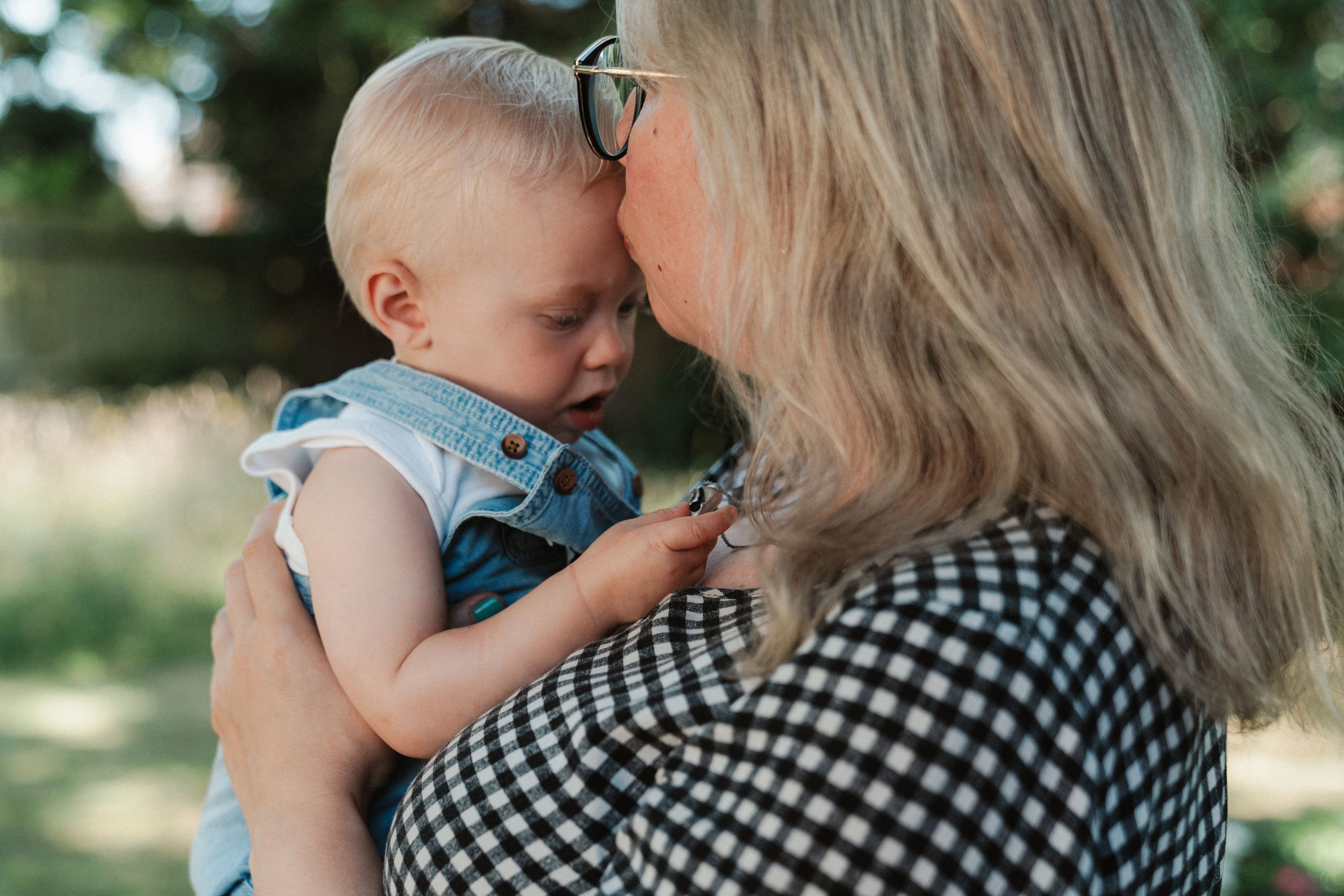 Close-up of tender family interaction against natural outdoor backdrop.