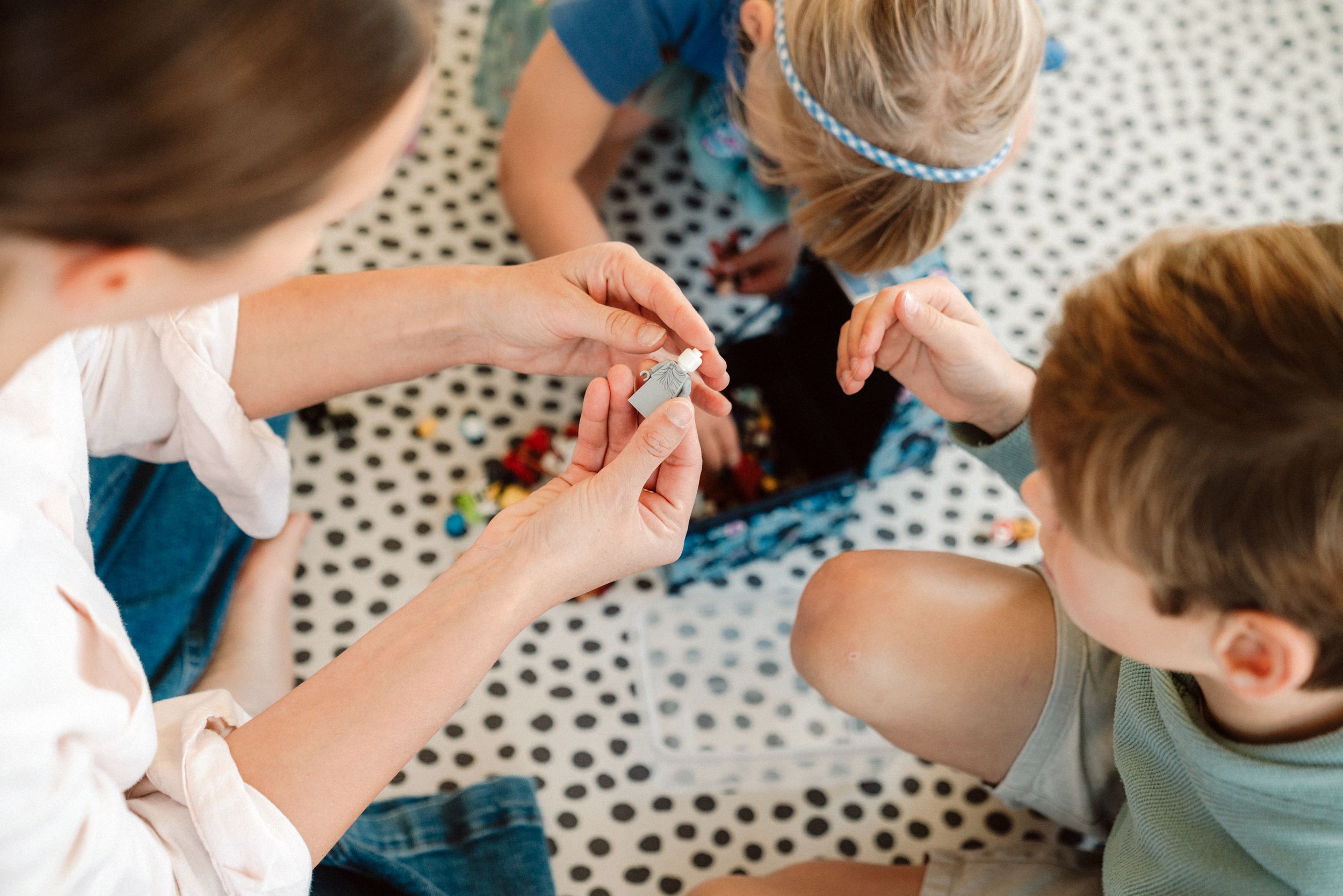 Children engaged in a hands-on creative activity at a polka dot table.