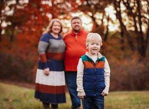 Family portrait with fall foliage background during golden hour.