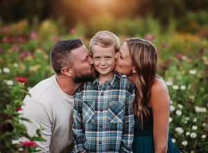 Sweet family moment captured in blooming flower garden during golden hour.